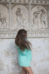 Young woman standing against wall