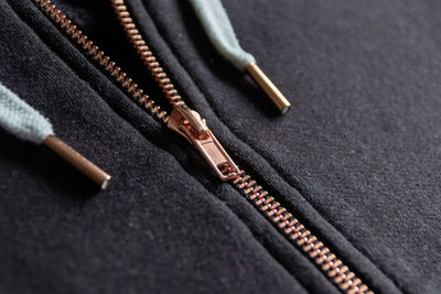 Copper colored fashion zipper in close-up macro view showing black sweatshirt with opened zipper