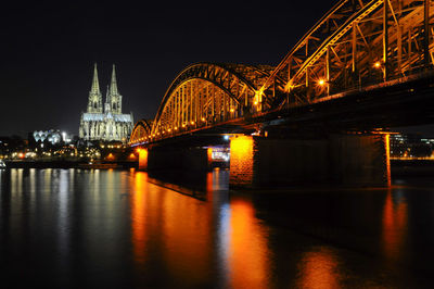 Illuminated hohenzollern bridge over rhine river with cologne cathedral against sky