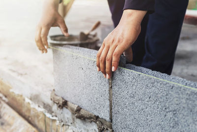 Midsection of man working on concrete wall