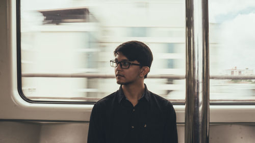Young man looking away while sitting in train