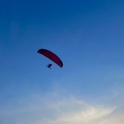 Low angle view of person paragliding against clear blue sky