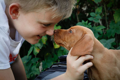 Side view of happy boy playing with puppy