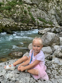 Cute girl sitting on rock by water