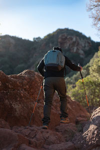 Middle-aged man climbs the mountain in the garraf natural park, supported by hiking poles.