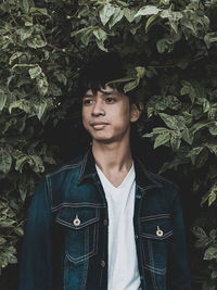 Portrait of young man standing against plants