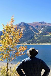 Rear view of man on mountain against clear blue sky