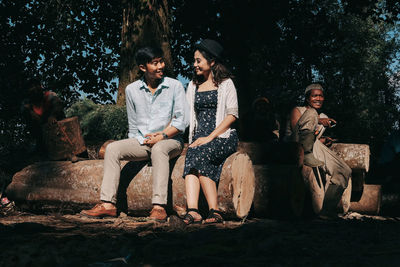 People sitting on rock against trees