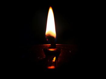 Close-up of lit candle in darkroom