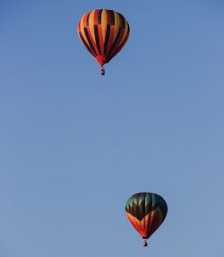 Low angle view of hot air balloons against clear blue sky on sunny day