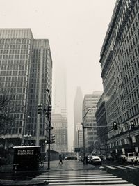 City street amidst buildings against sky during rainy season