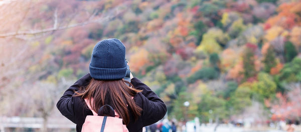 Rear view of woman standing by autumn leaves