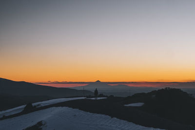 Scenic view of silhouette mountains against orange sky