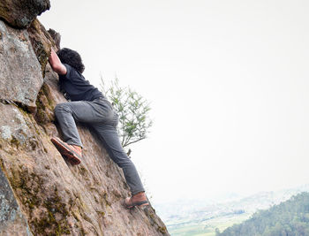 Man standing on rock against clear sky