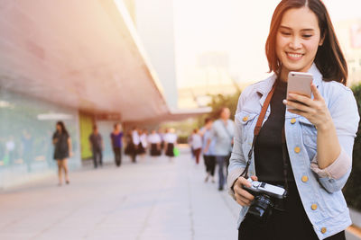 Full length of woman walking on mobile phone