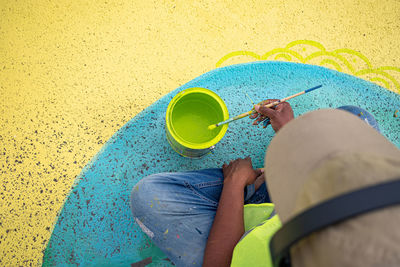 Low section of woman sitting with yellow umbrella