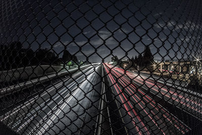 Road seen through chainlink fence at night