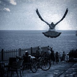 Bicycles on chair by sea against sky