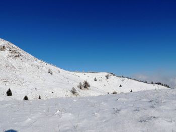 Scenic view of snowcapped mountains against clear blue sky