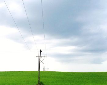 Electricity pylon on field against sky