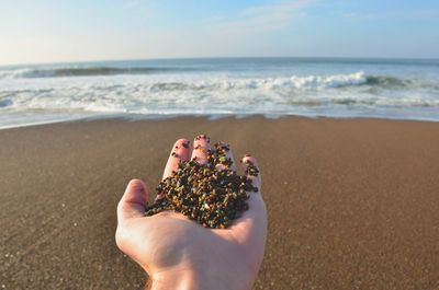 Midsection of person hand on sea shore