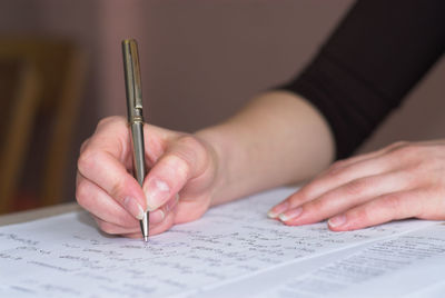 Cropped hand of woman writing on paper