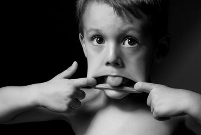 Portrait of man making face against black background