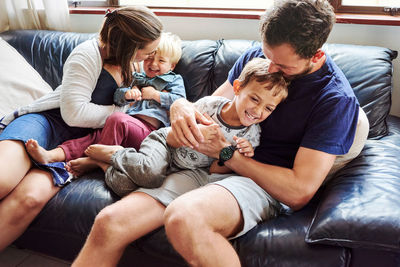 Parents and kids sitting on sofa at home