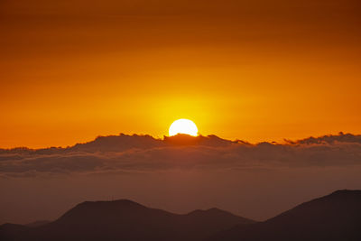 Scenic view of silhouette mountains against romantic sky at sunset