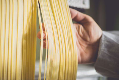 Cropped image of hand checking spaghetti drying in factory