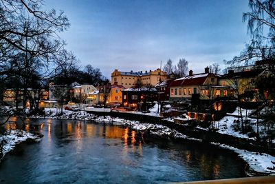 Bridge over river by buildings against sky in city