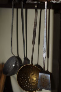 Close-up of ladles and spatulas hanging in kitchen