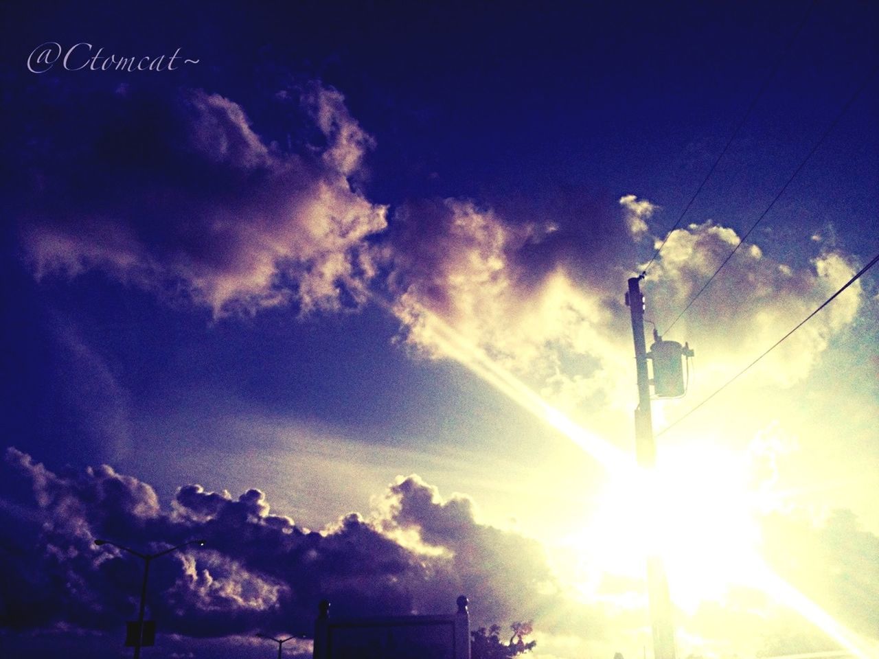 low angle view, sky, sun, sunbeam, street light, sunlight, silhouette, cloud - sky, lens flare, lighting equipment, blue, built structure, outdoors, building exterior, nature, no people, tree, cloud, pole, guidance