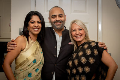 Portrait of smiling friends standing against door