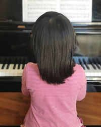 Rear view of girl playing piano