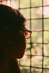 Close-up of boy looking through window