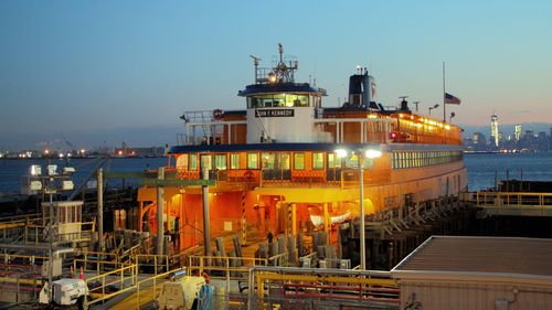 Boats moored at harbor against clear sky at night