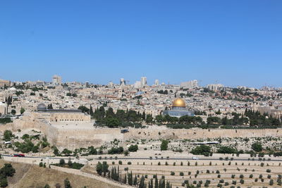 Aerial view of buildings in city against clear blue sky