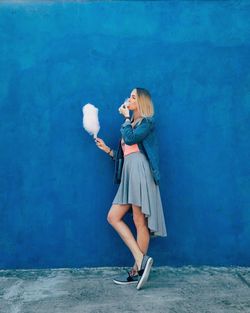 Young woman holding umbrella standing on wall