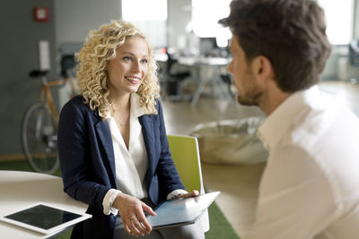 Businessman and woman discussing project in office, using digital tablet