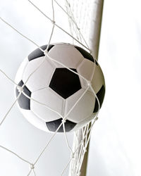 Close-up of soccer ball in net against white background