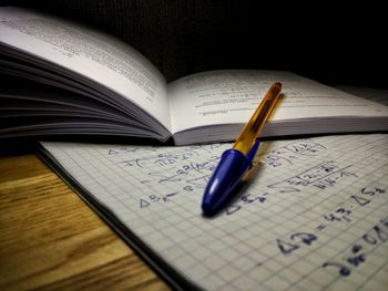 Close-up of open book and pen on table