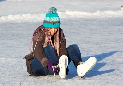 Full length of woman sitting on snow covered landscape