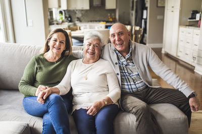 Portrait of multigenerational family sitting on living room couch