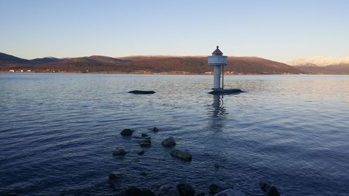 Lighthouse on lake against clear sky