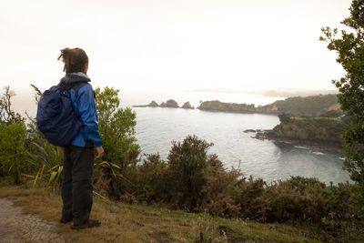 Rear view of man looking at lake against sky