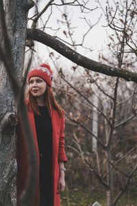 Young woman standing amidst trees in forest during winter