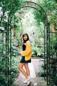 Portrait of smiling young woman standing against plants