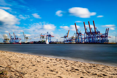 Cranes at commercial dock against sky