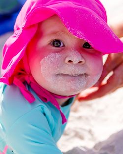 Close-up portrait of cute baby girl with sand on her face at beach